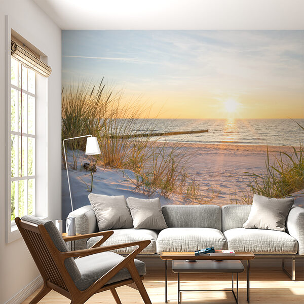 Fotobehang Gras op een strand met water op de achtergrond