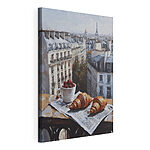 Canvas Schilderijen Kopje koffie en croissants op een tafel met gebouwen op de achtergrond